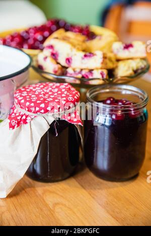 Gläser von leckeren Sommer Kirsche Marmelade mit gebackenen Kirsche Kuchen und rohe Kirschen Hintergrund Stockfoto