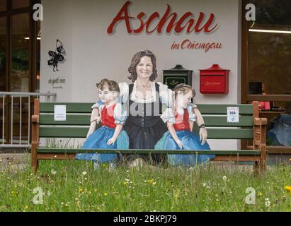 Aschau Im Chiemgau, Deutschland. Mai 2020. Vor der Tourist-Information steht während einer Fotosession eine Holzbank mit dem Bild von Ilse Aigner (CSU), Präsidentin des Bayerischen landtags, mit zwei Mädchen im Arm. 2014 schenkte Ilse Aigner die Bank "Ilse's Lausdirndlbankerl" an die Stadt Aschau im Chiemgau, auch bekannt als "Bankerldorf". Der Politiker war damals Bayerischer Wirtschaftsminister. Quelle: Peter Kneffel/dpa/Alamy Live News Stockfoto