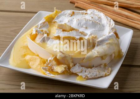 Französisches Camember Fondue Nahaufnahme mit Brotstäbchen auf einem Holztisch Stockfoto