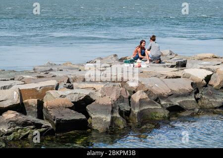 Barnegat, NJ, USA -- 13. September 2019. Foto von zwei jungen Frauen, die von einem Steinsteg in Barnegat Bay, NJ. Fischen Stockfoto