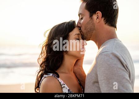 Ein Paar teilt sich einen romantischen Moment am Strand in der Dämmerung Stockfoto