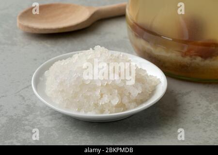 Schüssel mit Bio-Probiotikum Wasser Kefir Körner vor einem Glas mit Körnern und Früchten gefüllt Stockfoto