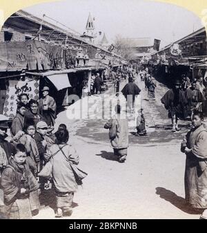 [ 1890er Jahre Japan - Geschäfte im Asakusa Sensoji Tempel in Tokio ] - Menschen gehen an den Nakamise Souvenirläden entlang der Annäherung an den buddhistischen Tempel Sensoji (金龍山浅草寺) in Asakusa, Tokio. Auch die Männer tragen noch Kimono. Im Hintergrund ist das Hozomon-Tor zu sehen. Vintage-Stereoansicht aus dem 19. Jahrhundert. Stockfoto