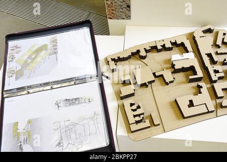 Ein Architekturmodell mit Zeichnungen in einem Portfolio. Ein angehende Architekt stellt seine Arbeiten auf einer Jahresendschau aus. Stockfoto
