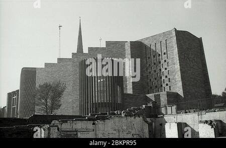 1962, historisches Bild mit der Fassade der neu erbauten Kathedrale, Coventry, England, mit dem Turm der alten Kathedrale noch stehend. Im 2. Weltkrieg schwer bombardiert, im Mai 1962 ein neues Gebäude im 'modernistischen' Stil, Die von Basil Spence entworfene Architektur wurde offiziell auf dem Gelände der Ruinen der alten Kathedrale eröffnet.Diese Form der Nachkriegsarchitektur, die aufgrund ihrer radikalen Entwürfe als "Brutalist" bekannt ist, war in dieser Zeit sehr beliebt und Spence war einer der führenden Lichter. Stockfoto