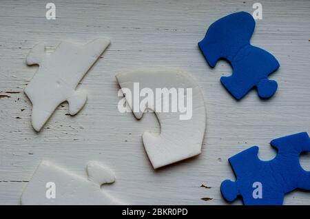 Zerlegte Puzzleteile auf weißer, rissiger Farbe. Blau-weiße Puzzleteile auf einem alten Holztisch. Das Konzept eines alten ungelösten Problems. Psychol Stockfoto