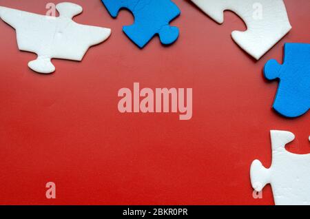 Fünf Puzzleteile auf einem farbigen Hintergrund. Blaue und weiße Teile eines unmontierten Puzzles um den Rand des Bildes. Multitasking kontrastierend b Stockfoto