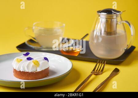 Zitronenkuchen mit Tee auf gelbem Hintergrund. Traditioneller französischer Kuchen. Köstliches, leckeres, hausgemachtes Dessert mit Zitronencreme. Kopierbereich Stockfoto