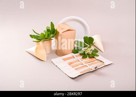 Umweltfreundliches Einweggeschirr aus Bambusholz und Papier auf grauem Hintergrund. Drapierte Löffel, Gabel, Messer, Teller mit. Recyclingkonzept. Kopierbereich. Stockfoto