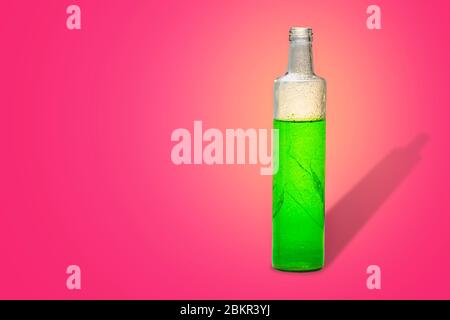 Glasflasche mit grünem erfrischendem Kräutergetränk im rosa Hintergrund Stockfoto