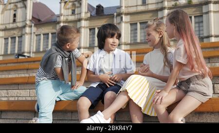 Vier Kinder sitzen zusammen lächelnd und reden. Stockfoto