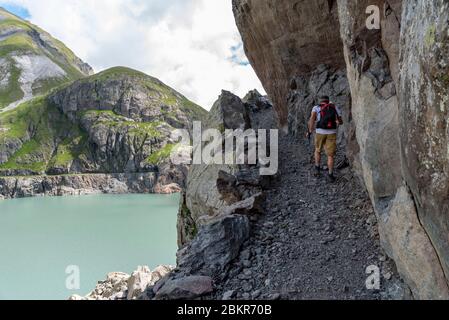 Schweiz, Wallis, Trient-Tal, Finhaut, Lac d'Emosson, Pointe de la Terrasse, Wanderer auf einem Weg in den Felsen gehauen und mit Blick auf den Lac du Vieux Emosson Stockfoto