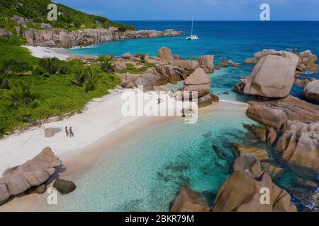 Seychellen, Digue Island, Anse Marron, Segelboot Liegeplätze 4800 vor Anker, Mann und Frau am Strand und Granitfelsen (Luftaufnahme) Stockfoto