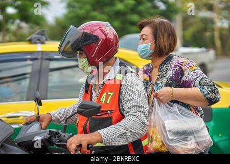 Ein Motorrad-Taxifahrer und Passagier, mit Schutzmaske, in Pathumthani, Thailand, im Mai 2020. Stockfoto