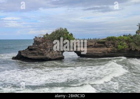 Wellen kommen an einer Felsklippe unterhalb des Batu Bolong Tempels an. Tanah Lot Tempel. Riesiges Loch in Felsklippe unterhalb Pura Batu Bolong Tempel. Hindu-Tempel auf der Be Stockfoto