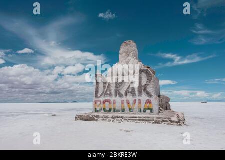 Großes Felsschild von Dakar Bolivien in den Salzebenen unter einem blauen Himmel mit weißen Wolken. Stockfoto