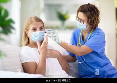 Arzt untersucht kranken Patienten in Gesichtsmaske. Kranke Frau in der Klinik für Test und Screening. Behandlung von Viren zu Hause. Coronavirus-Pandemie. Covid-19 Stockfoto
