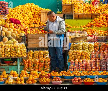 Obsthändler auf dem lokalen Markt von Otavalo in der Nähe von Quito, Ecuador. Scharfes Gesicht, unscharfe Frucht. Stockfoto