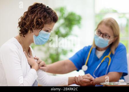 Arzt untersucht kranken Patienten in Gesichtsmaske. Kranke Frau in der Klinik für Test und Screening. Behandlung von Viren zu Hause. Coronavirus-Pandemie. Covid-19 Stockfoto