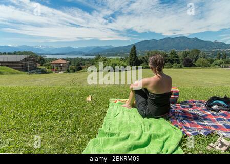 Einsames Mädchen entspannt auf einem Gras sitzen und schaut auf den Horizont. Blauer Himmel. Entspannendes Konzept. Stockfoto