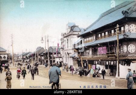 [ 1900er Japan - belebte Straße in Yokohama ] - Bashamichi-dori in Yokohama, Präfektur Kanagwa. Das große Gebäude ist Tomitake-tei, ein sehr beliebtes Theater, das 1878 eröffnet wurde (Meiji 11). Vintage-Postkarte des 20. Jahrhunderts. Stockfoto