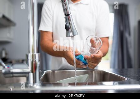 Leitender Mann, der in seiner modernen, hellen Küche Geschirr spült (flaches DOF; Farbbild) Stockfoto