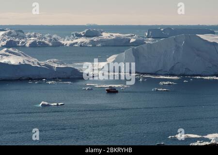 Teleaufnahme des Bootes zwischen den Eisbergen in der Disko Bucht Ilulissat Stockfoto