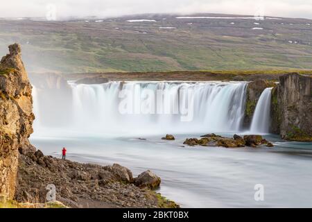 Langzeitbelichtung eines anderen Fotografen, der ein Foto des Goðafoss-Wasserfalls, eines 12 m hohen Sturzes über 30 m des Flusses Skjálfandafljót Island, machte. Stockfoto