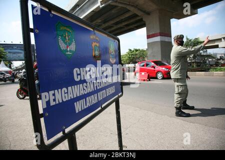 Bekasi, Indonesien. Mai 2020. Beamte überwachen Autofahrer, die am Dienstag (5/2020) an der Grenzstraße Sumber Artha, Kalimalang, Bekasi City, West Java, Indonesien, vorbeifahren. (Foto von Kuncoro Widyo Rumpoko/Pacific Press) Quelle: Pacific Press Agency/Alamy Live News Stockfoto