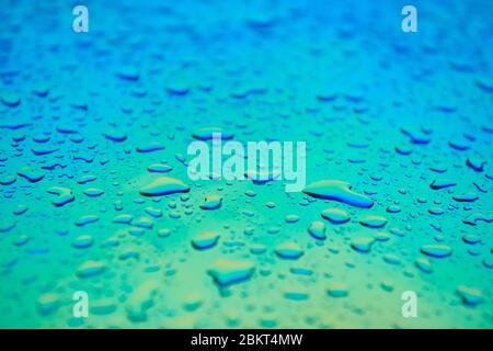 Wassertropfen auf der holographischen Chamäleon-Oberfläche. Schöner farbenfroher Hintergrund mit geringer Schärfentiefe. Blauer und aquamarinfarbener Gradient. Stockfoto