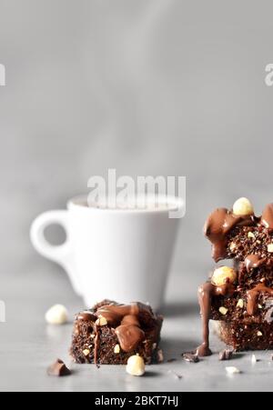 Stapel von einem Brownie Stücke mit Haselnuss und Tasse auf einem grauen Tisch mit grauem Hintergrund. Stockfoto
