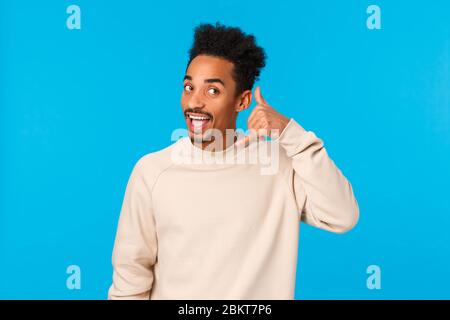 Hallo Whos anrufen. Lustiger attraktiver und fröhlicher Flusspferd afro-amerikanischer Kerl mit Haarschnitt, Schnurrbart, imitierendem Telefonanruf, das Handy macht Stockfoto