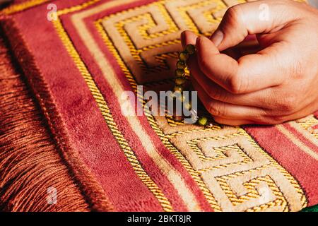 In der Hand halten muslimische Gebetsperlen tasbih für das Gebet auf Matte in Ramadan Kareem Stockfoto