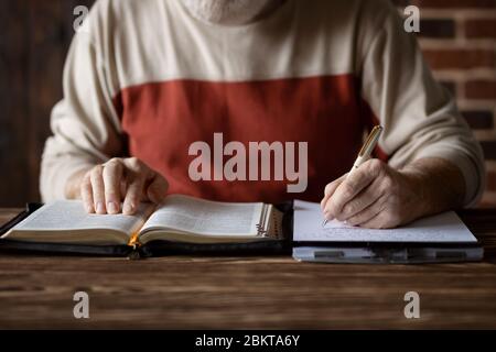 Bibelstudium nach dem Wort der Schrift und kopieren es auf Papier. Notizen machen und die Bibel studieren. Suche nach einem spirituellen Thema Stockfoto