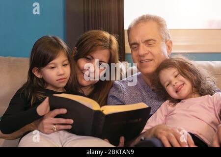 Großeltern, die Enkelkinder über die Heilige Bibel unterrichten Stockfoto