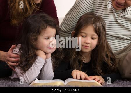 Großeltern, die Enkelkinder über die Heilige Bibel unterrichten Stockfoto