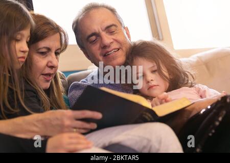 Großeltern, die Enkelkinder über die Heilige Bibel unterrichten Stockfoto