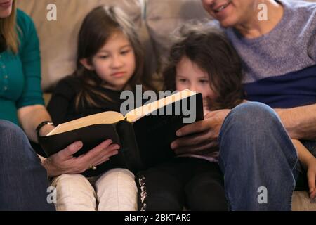 Großeltern, die Enkelkinder über die Heilige Bibel unterrichten Stockfoto