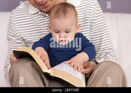 Großvater liest seinem jungen Enkel Geschichten aus der Heiligen Bibel vor Stockfoto