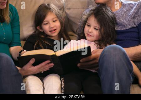 Großeltern, die Enkelkinder über die Heilige Bibel unterrichten Stockfoto