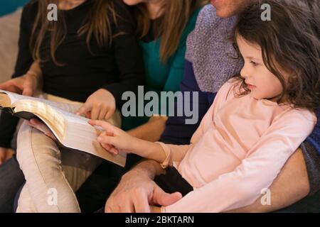 Großeltern, die Enkelkinder über die Heilige Bibel unterrichten Stockfoto