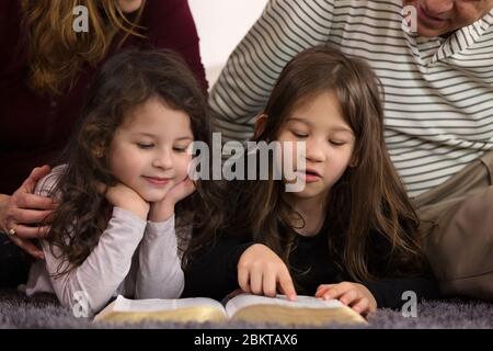 Großeltern, die Enkelkinder über die Heilige Bibel unterrichten Stockfoto