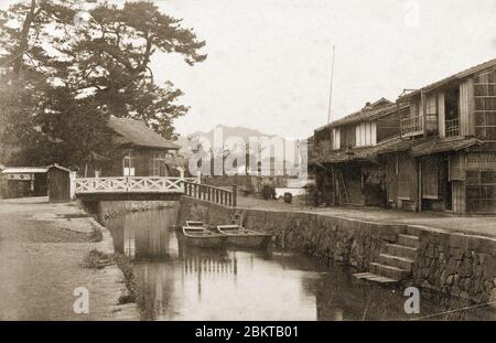 [ 1880er Jahre Japan - Prostitution District in Matsue ] - EINE seltene frühe Meiji Periode (1868-1912) Foto der Shoukabashi Brücke (松花橋) über den Wadamigawa Fluss (和田見川) im Prostitution Bezirk Wadami-Shinchi (和田新地遊郭) in Matsue, Shimane Präfektur, um 1880er Jahre. Hinter der Brücke ist der schintoistische Schrein Mefu Jinja (賣布神社) zu sehen. Der Fluss wurde in der frühen Showa-Periode (1926-1989) gefüllt. Vintage Albumin-Fotografie aus dem 19. Jahrhundert. Stockfoto