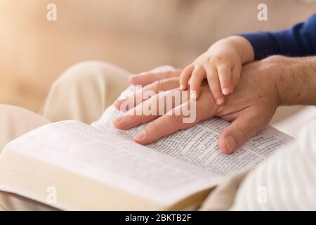 Großvater liest seinem jungen Enkel Geschichten aus der Heiligen Bibel vor Stockfoto