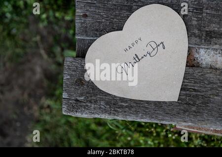 Happy Mother's Day auf einer Papierkarte auf einer rustikalen alten Bank geschrieben Stockfoto