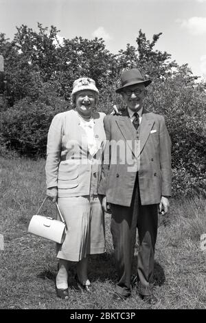 1950er, historisch, draußen trägt Tbeir Sonntag am besten, vielleicht für eine Hochzeit, da sie beide tragen Hüte, ein reifes älteres Paar posieren für ein Bild, England, Großbritannien. Stockfoto