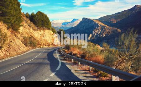 Malerische leere kurvenreiche Landstraße, die zu einem schneebedeckten Bergrücken der Sierra Nevada führt. Foto aufgenommen in Granada spanische Stadt, Skigebiet. Sonniger Tag Stockfoto
