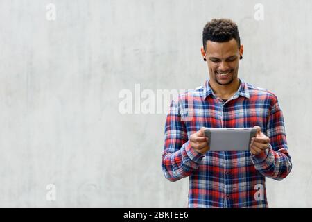 Glücklich junge schöne afrikanische Hipster Mann mit digitalen Tablet im Freien Stockfoto