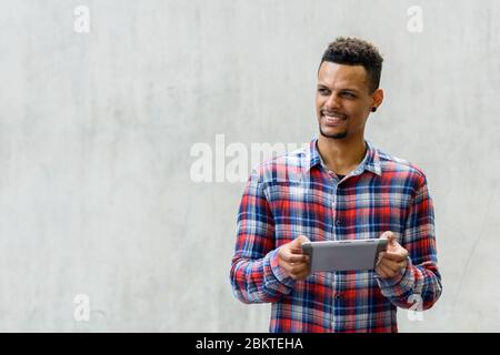 Glücklich junge afrikanische Hipster Mann denken, während mit digitalen Tablet im Freien Stockfoto