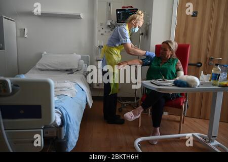 Eine Mitarbeiterin des klinischen Personals trägt persönliche Schutzausrüstung (PSA), während sie den Patienten Trudy Woodfall betreut, der sich auf der Covid Recovery Station im Royal Papworth Hospital in Cambridge vom Coronavirus erholt. Stockfoto